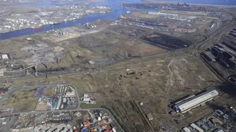 Teesworks An aerial view of Teesworks. An industrial estate can be seen to the bottom left while a large amound of undeveloped land is in the centre of the screen. The River Tees can be seen at the top of the picture.