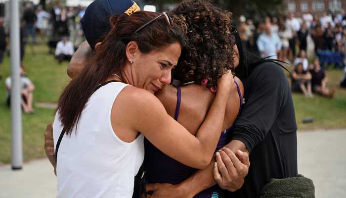 People embrace as they visit a makeshift memorial following the attack on a Jewish holiday celebration at Sydneys Bondi Beach, in Sydney, Australia on December 15, 2025. — Reuters